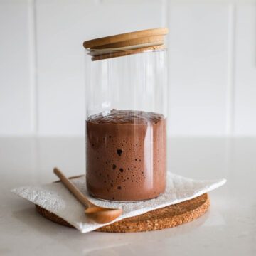 Chocolate sourdough starter in a jar with spoon.
