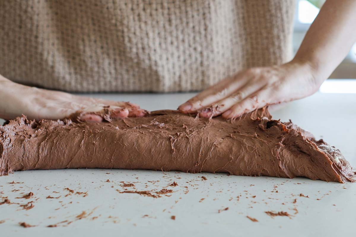 Hands folding chocolate dough.