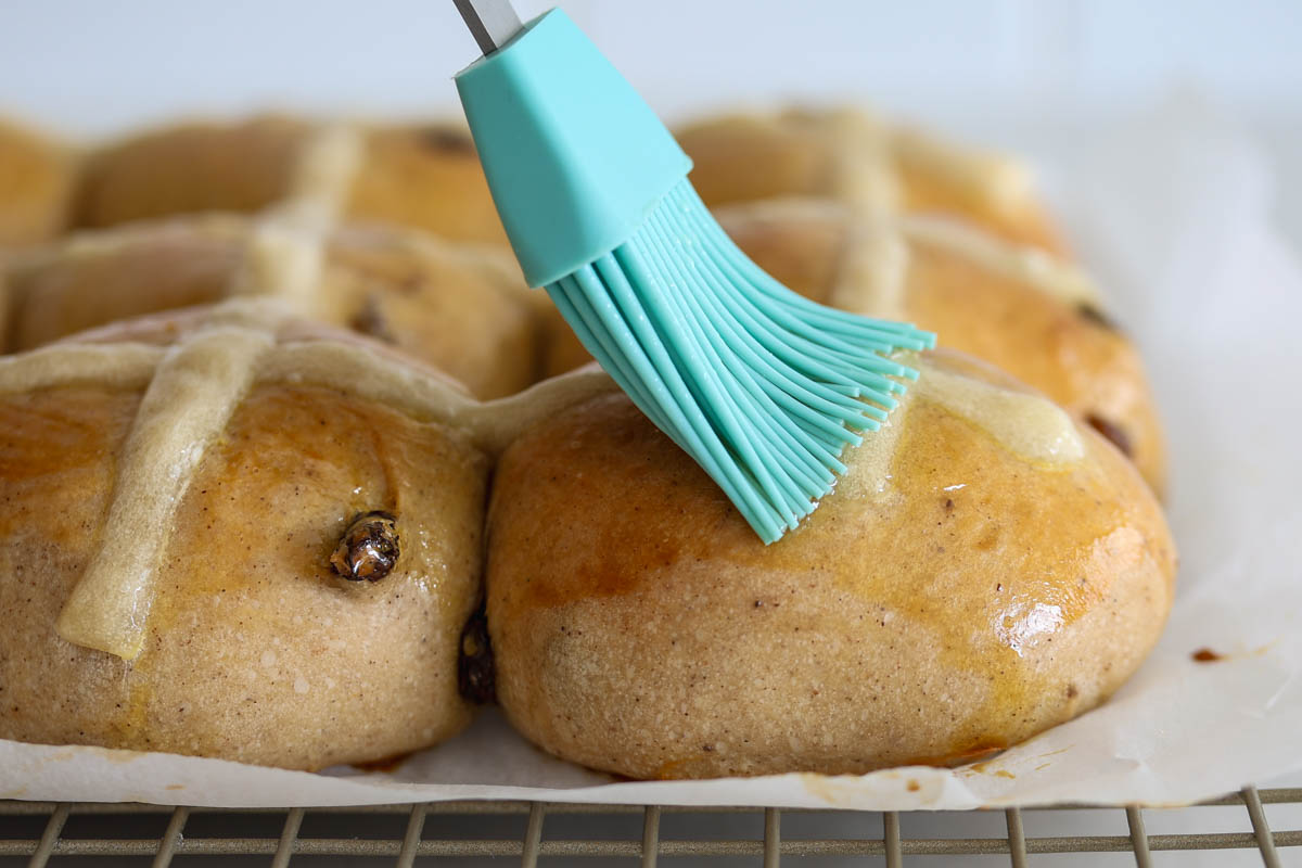 Brush brushing honey over baked buns.