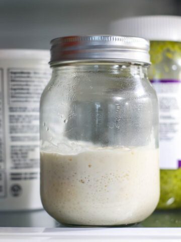 A sourdough starter in a closed jar inside the fridge.