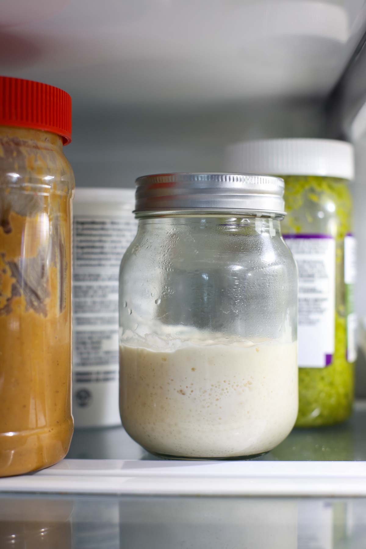 A sourdough starter in a closed jar inside the fridge.