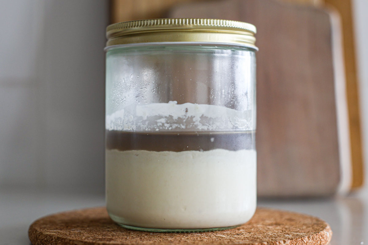 A sourdough starter flat with no bubbles and a layer of hooch.