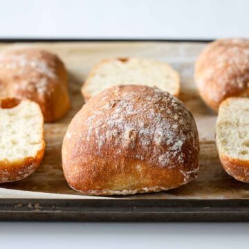 Sourdough ciabatta bread rolls on a baking pan.