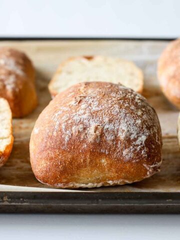 Sourdough ciabatta bread rolls on a baking pan.