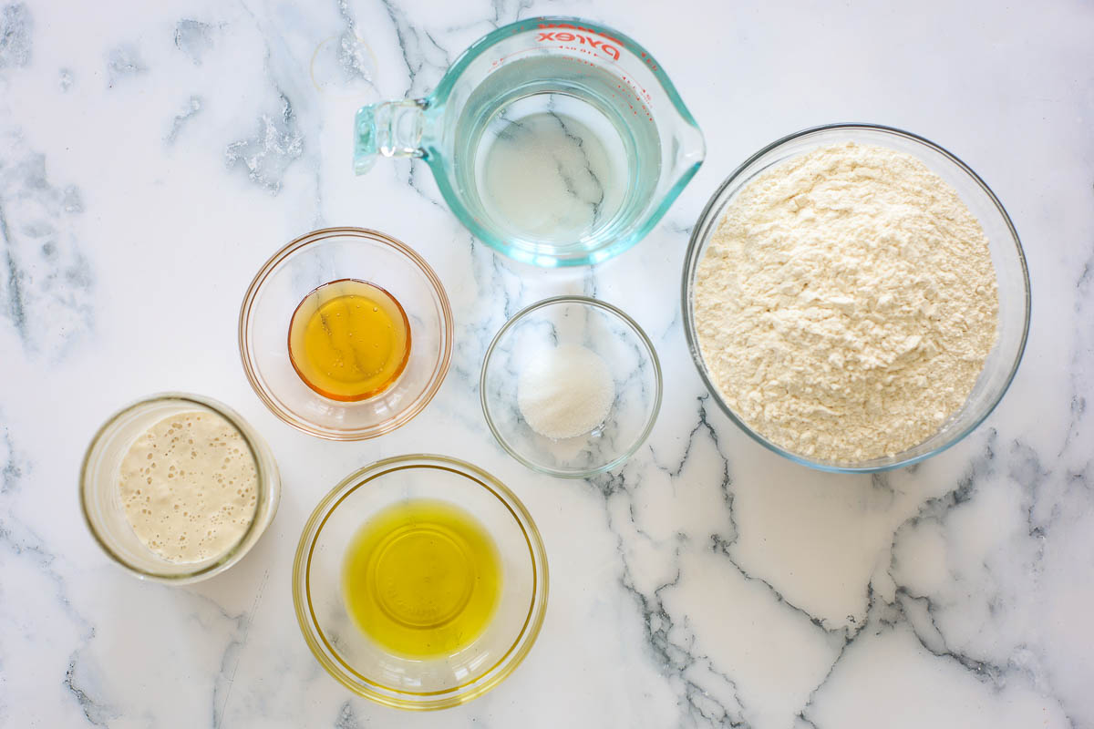 Sourdough focaccia ingredients: active sourdough starter, honey, olive oil, salt, water and flour.