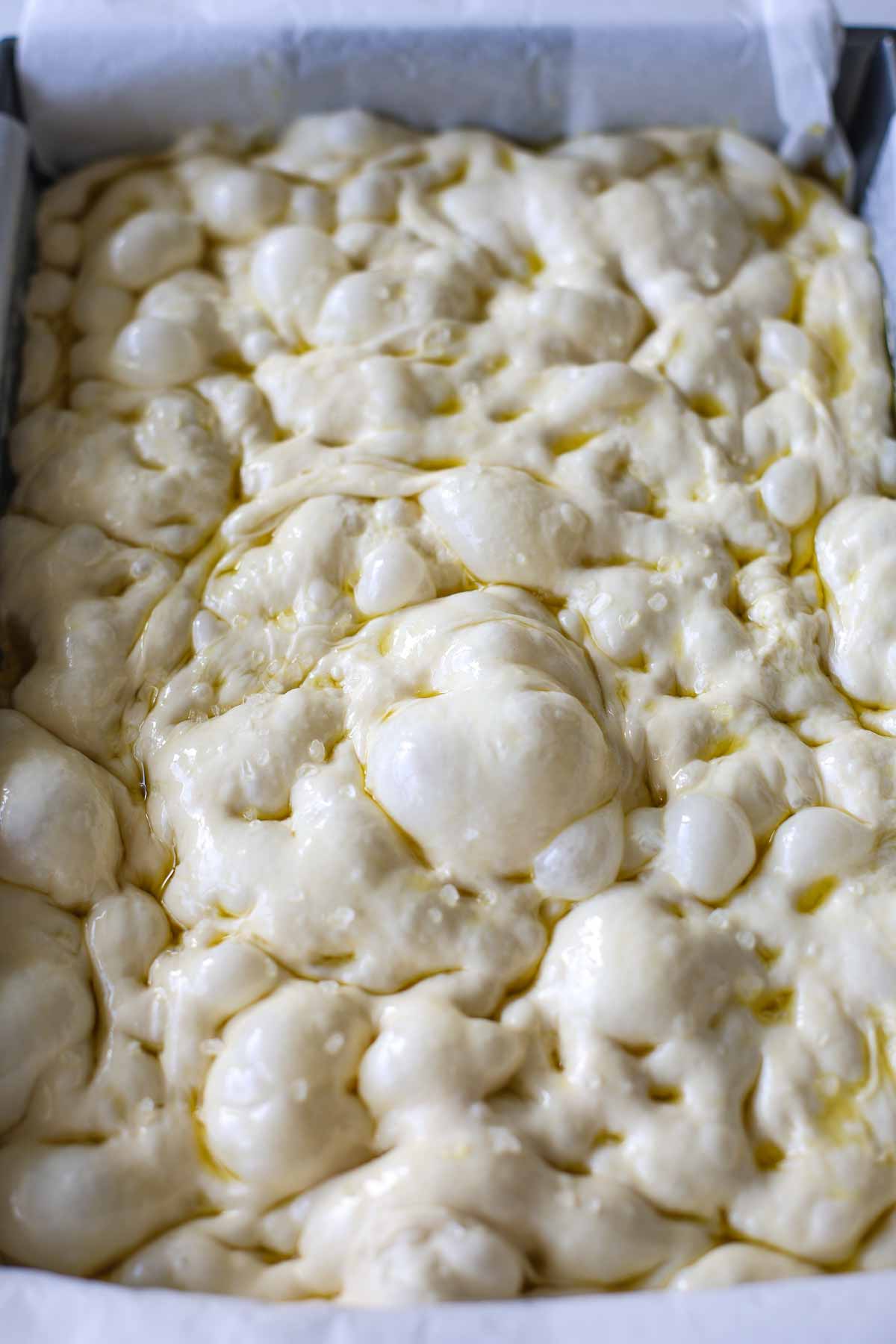 Focaccia dough with dimples, olive oil and flaky salt.